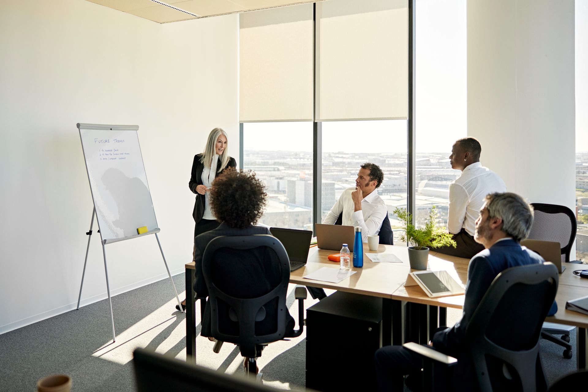 Colleagues engage in a strategic business meeting in a contemporary London office with city views.